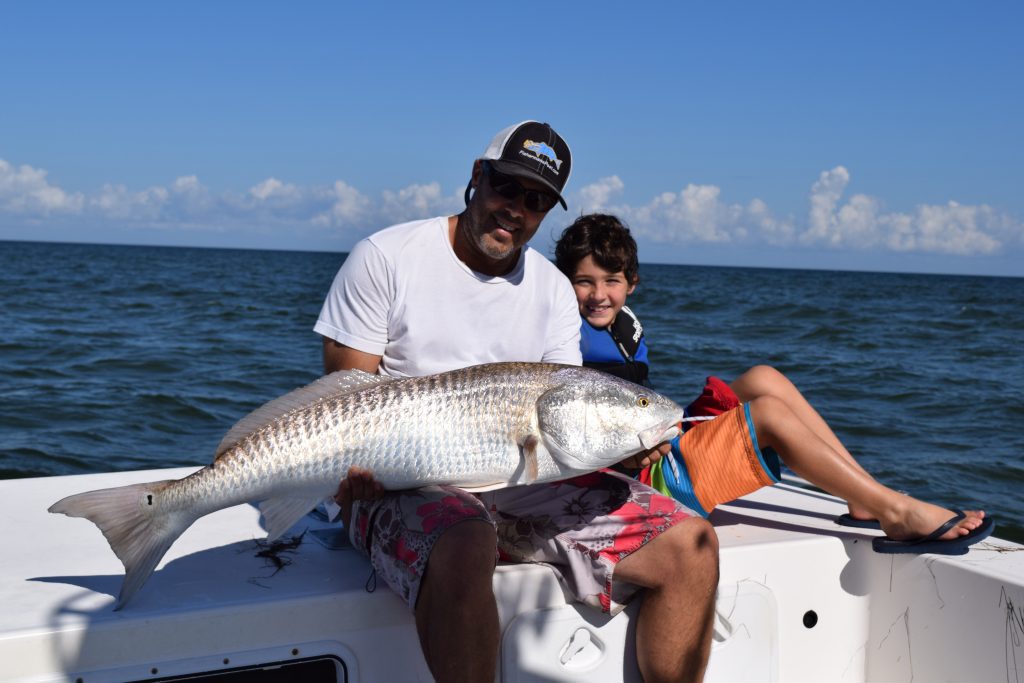 Publisher Gary Hurley and his son James (age 8) with a 45" red drum that was caught and released on a gold spoon by sight casting to a school of 50+ fish in the shallows behind Hatteras. They were fishing with Capt. Aaron Aaron of Tightline Charters out of Hatteras Harbor Marina.