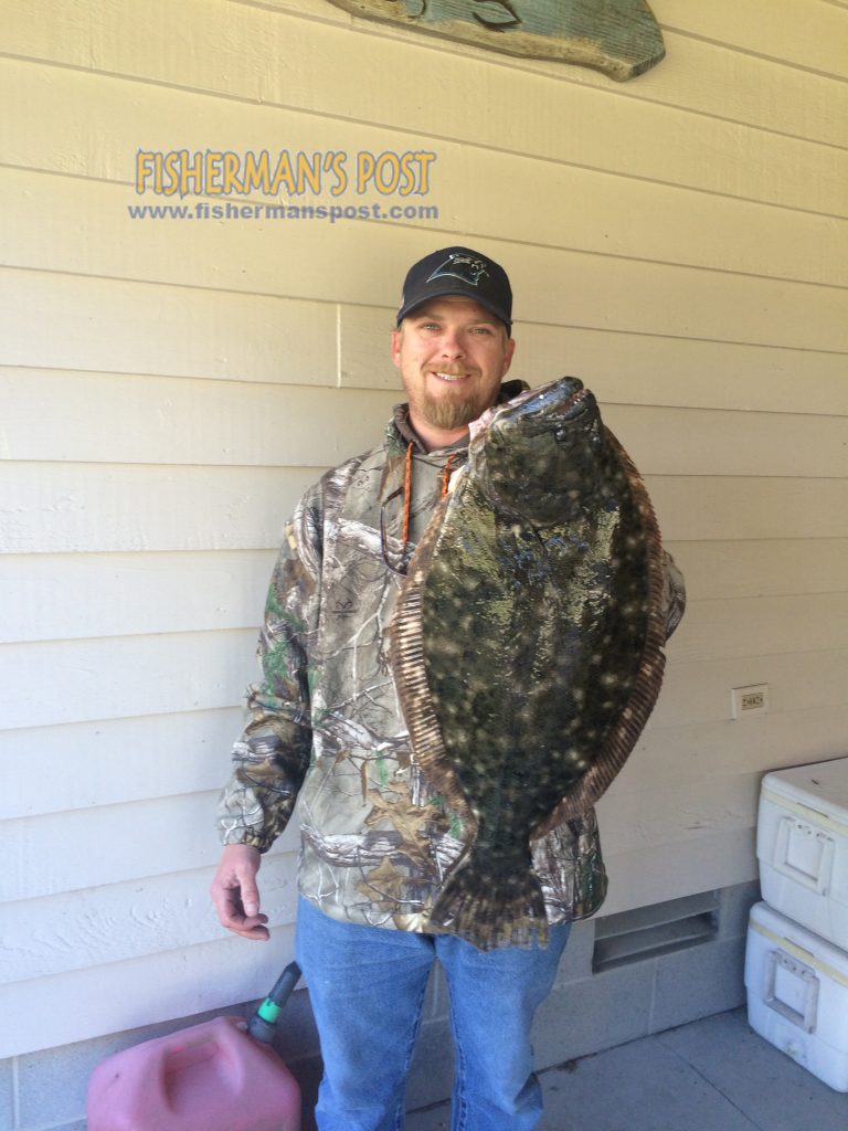 Brad Hasty, of Emerald Isle, with a 23" flounder he hooked while casting a green grub near the Morehead City port wall.